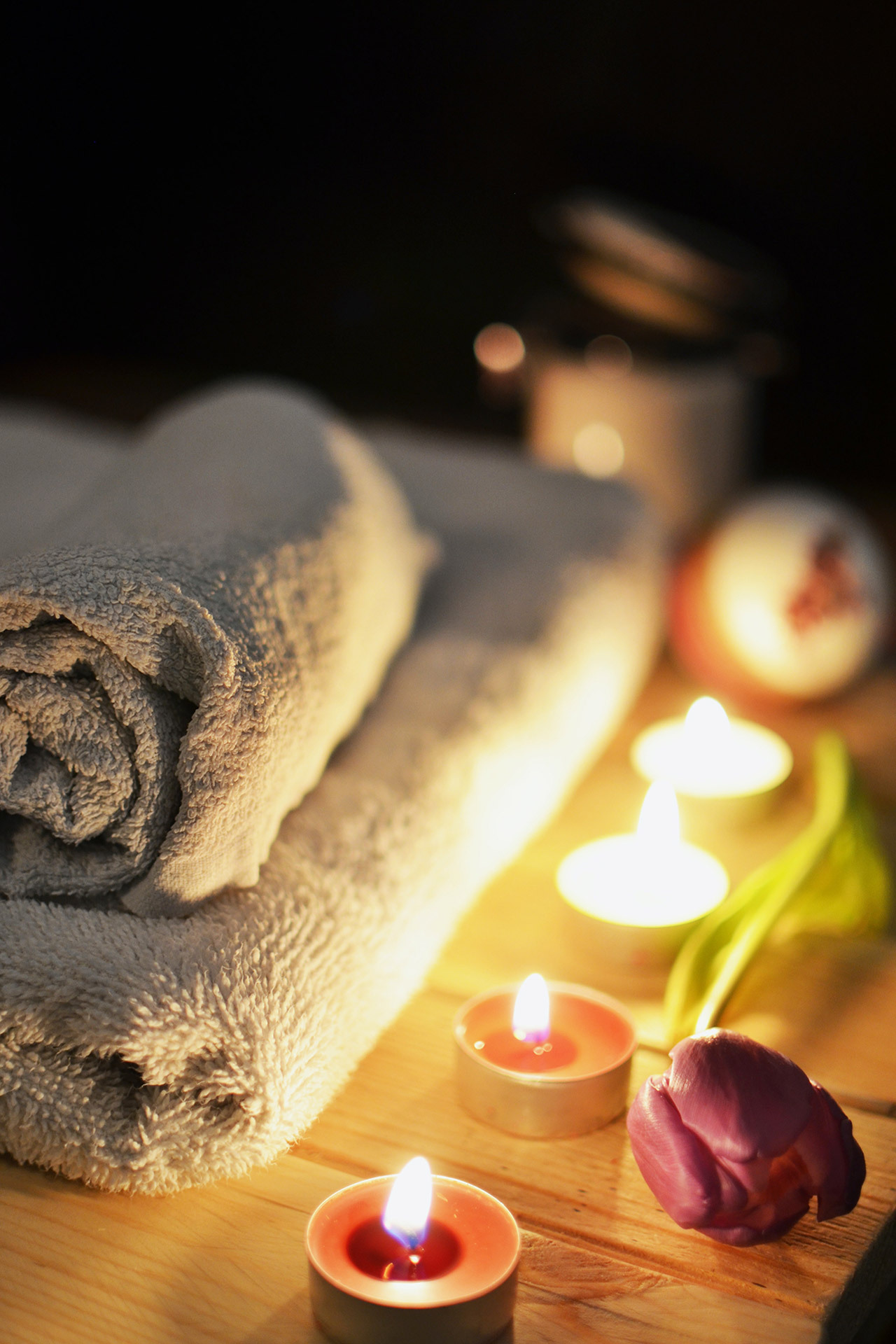 Photograph to signify self-care, showing a composition of soft towels, candles and flowers